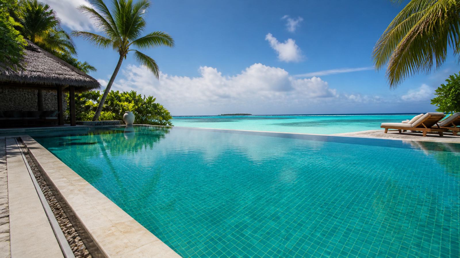 A resort swimming pool with clear turquoise water and an infinity edge over the lagoon