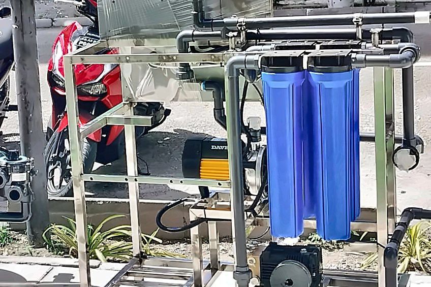 Stainless filtration skid with blue cartridge housings, pump and manifold pipework