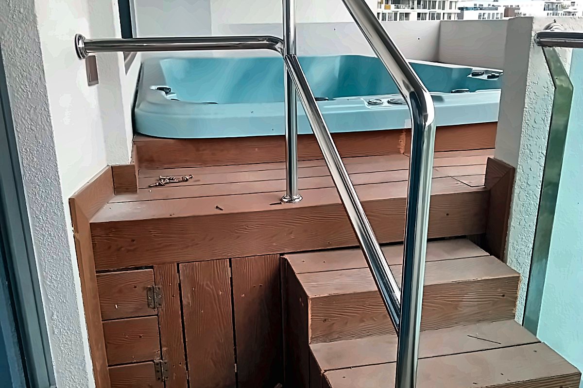Completed rooftop spa set into a hardwood deck with a stainless steel handrail